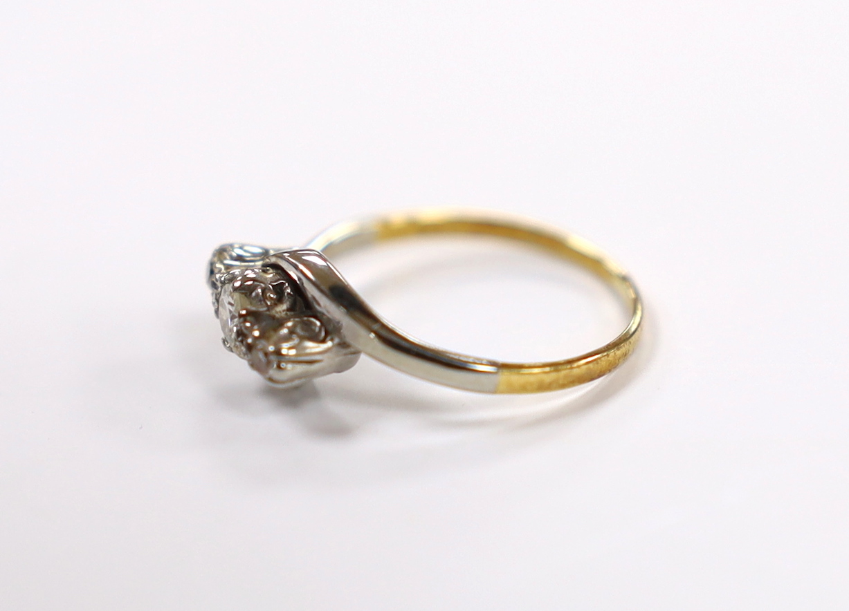 A yellow metal and three stone diamond set crossover ring, size H/I, gross weight 2 grams.
